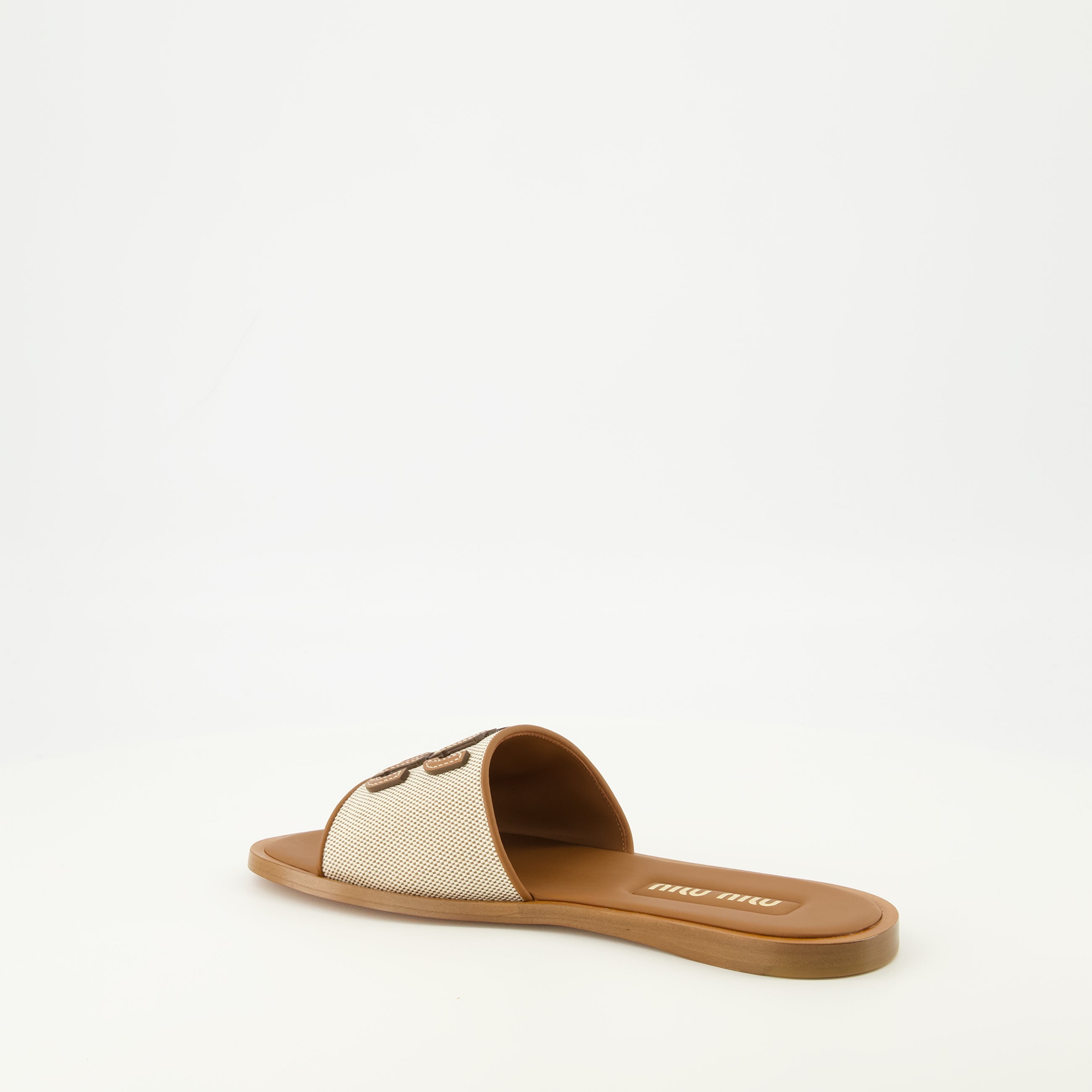 Imagen de las Mules de lona y cuero marrón de la marca Miu Miu para mujer - Temporada Primavera-Verano 2026 - Vista tres cuartos trasera derecha