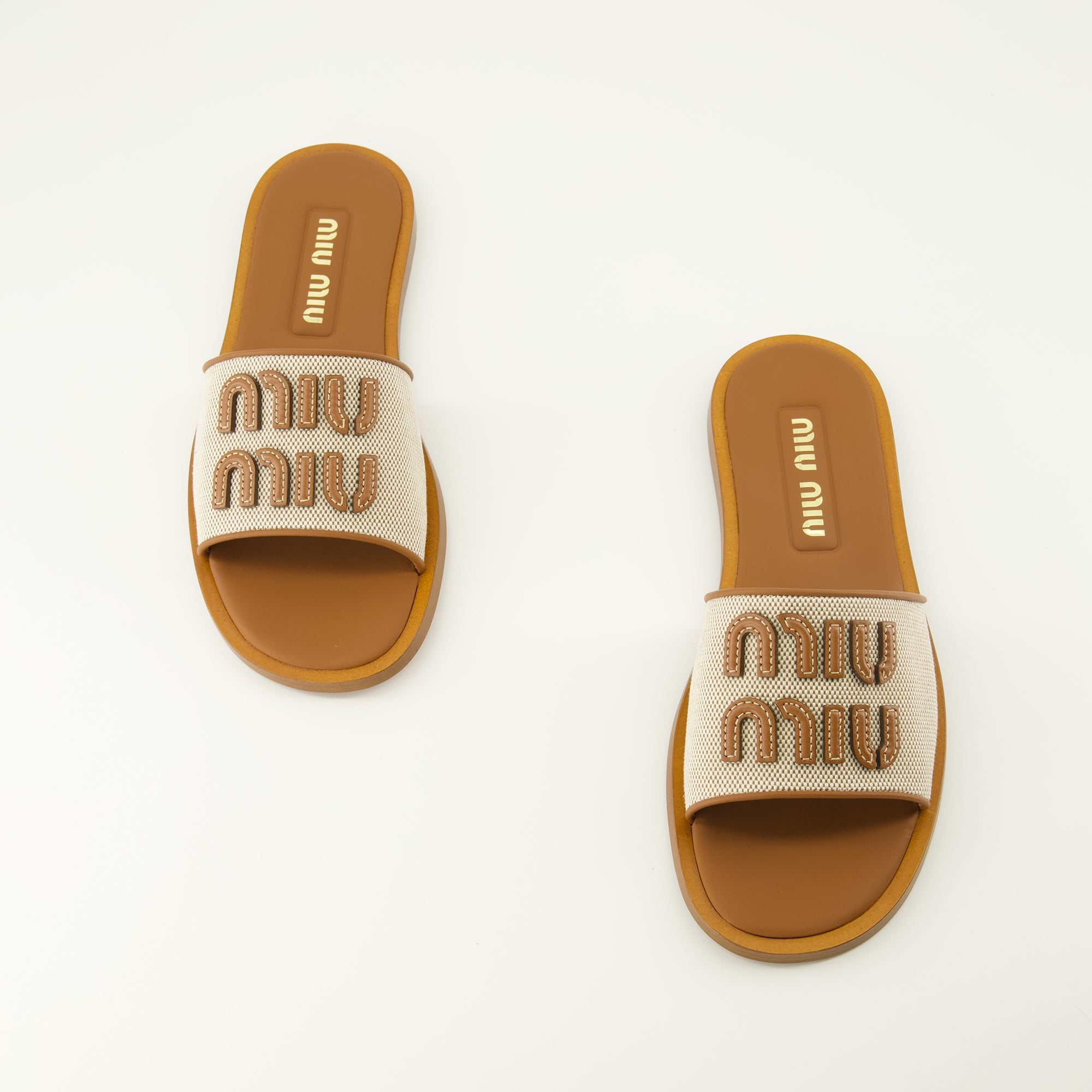 Imagen de las Mules de lona y cuero marrón de la marca Miu Miu para mujer - Temporada Primavera-Verano 2026 - Vista de cima do par de sapatos